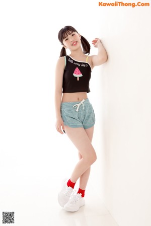 A young woman wearing a black top and blue shorts.