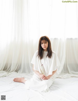 A woman laying on a bed with a flower in her hand.