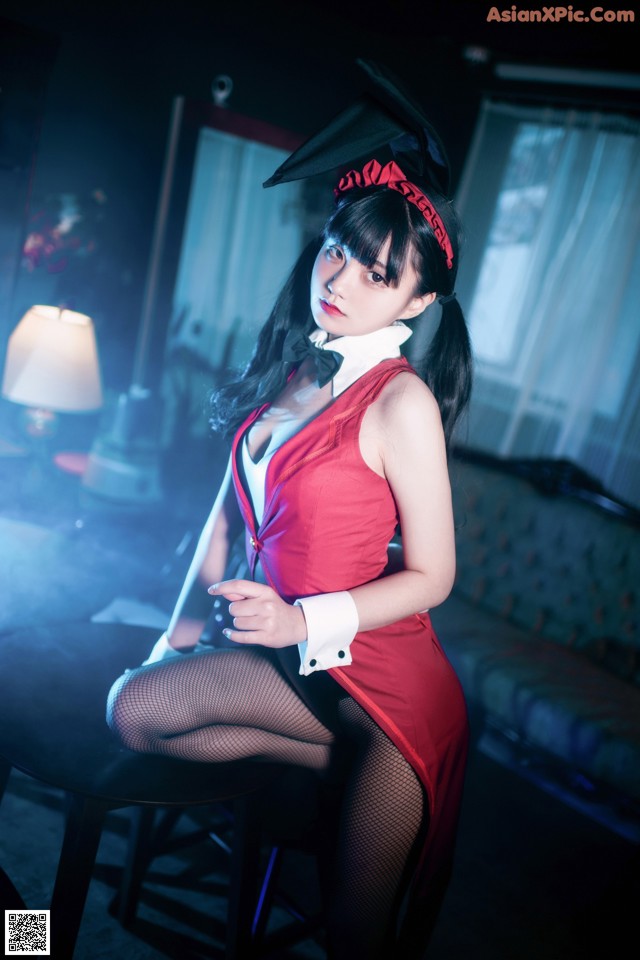A woman in a red dress sitting on a chair.