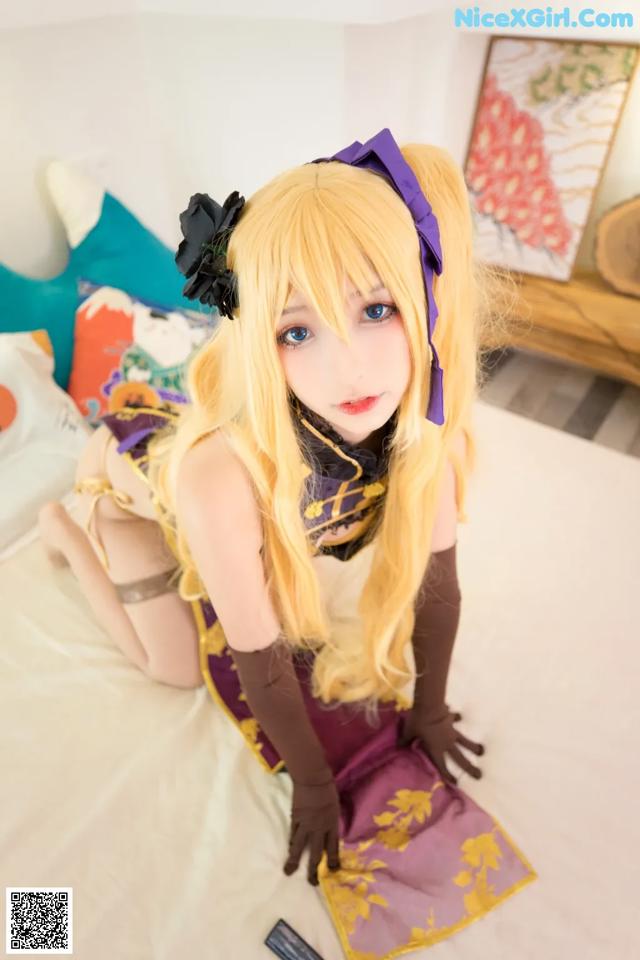 A woman with long blonde hair sitting on a bed.