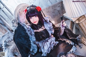 A woman in a black dress sitting on a couch.
