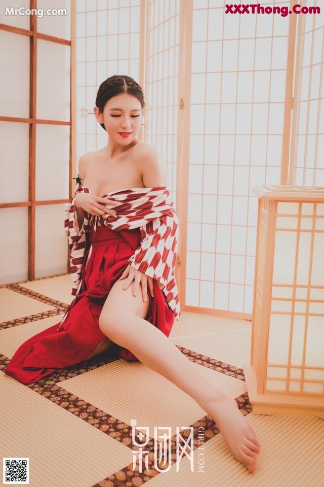 A woman in a red and white kimono sitting on the floor.