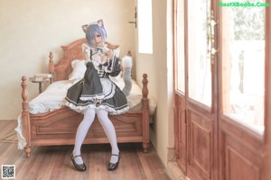 A woman in a maid outfit standing on a bed.