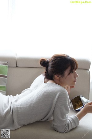A woman sitting on the floor in front of a refrigerator.