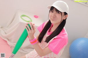 A woman in a pink and white striped dress holding a green ball.