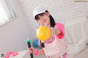 A woman in a pink and white striped baseball uniform posing for a picture.