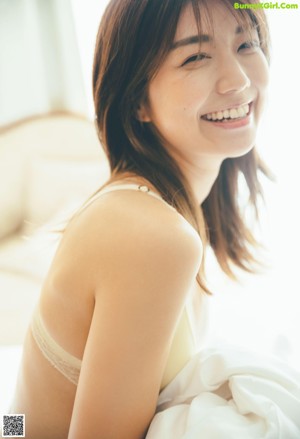 A woman is opening a door with a smile on her face.