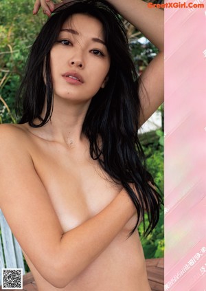A naked asian woman sitting on a wooden bench.