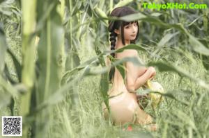 A woman in a bikini and straw hat standing in a field.