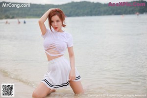 A woman in a bunny costume sitting on a beach.