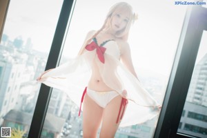 A woman in a white lingerie posing by a window.