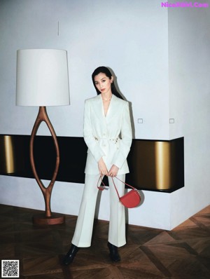 A woman standing in front of a desk holding a blue bag.