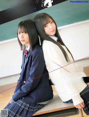 A couple of girls sitting on top of a wooden floor.