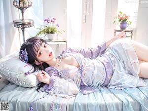 A woman in a blue kimono sitting on the ground.