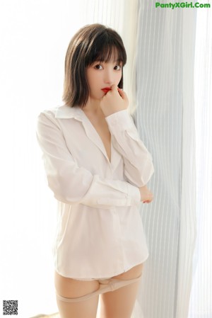A woman in a school uniform leaning against a curtain.