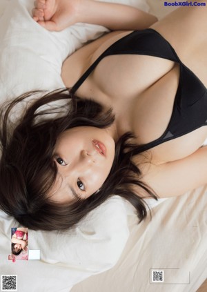 A woman in a pink bikini sitting on a bed.