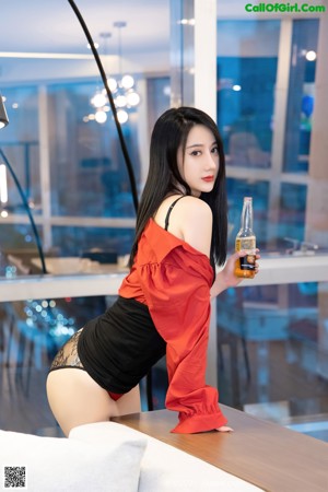A woman in a red shirt and black stockings sitting on a white couch.