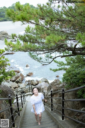 A woman in a white dress looking out of a window.