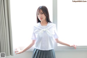 A woman in a white shirt and gray skirt posing for a picture.