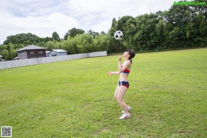 A woman in a bikini sitting on top of a wooden box holding a volleyball.