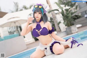 A woman in a purple bikini sitting on a blue couch.